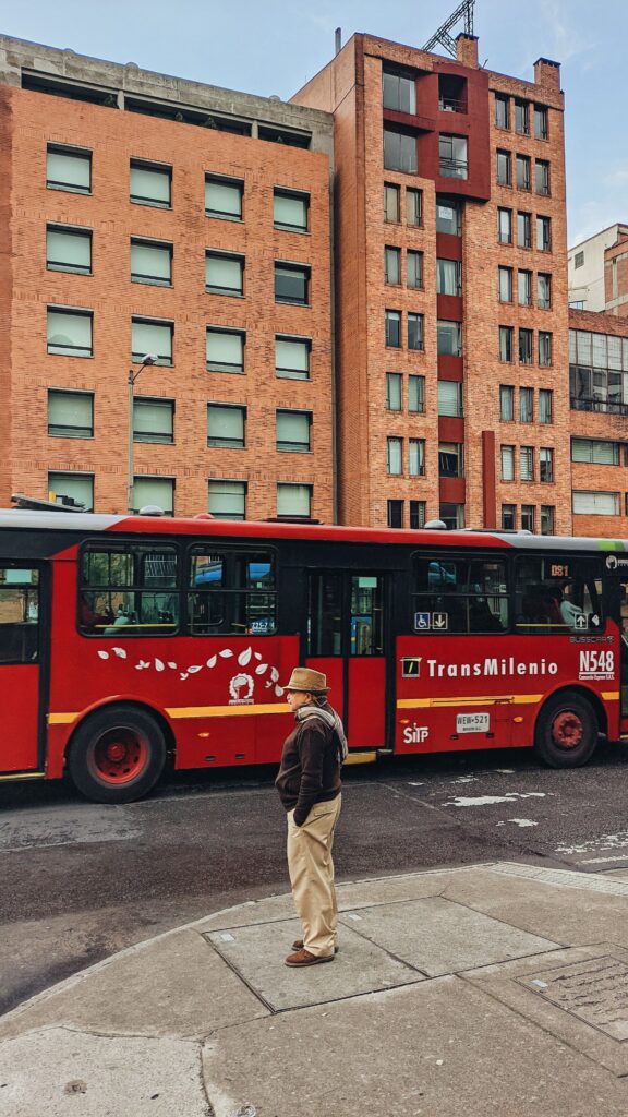 Calle de Bogotá con bus de TransMilenio y edificios de ladrillo